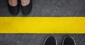 Legs of a couple standing opposite each other divided by the yellow asphalt line top view