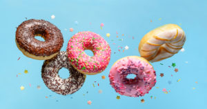 Picture of flying glazed and colored donuts. Six donuts in all of various hues and also coatings, which are falling into the air